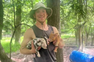 The owner of Heritage Homestead holding two piglets